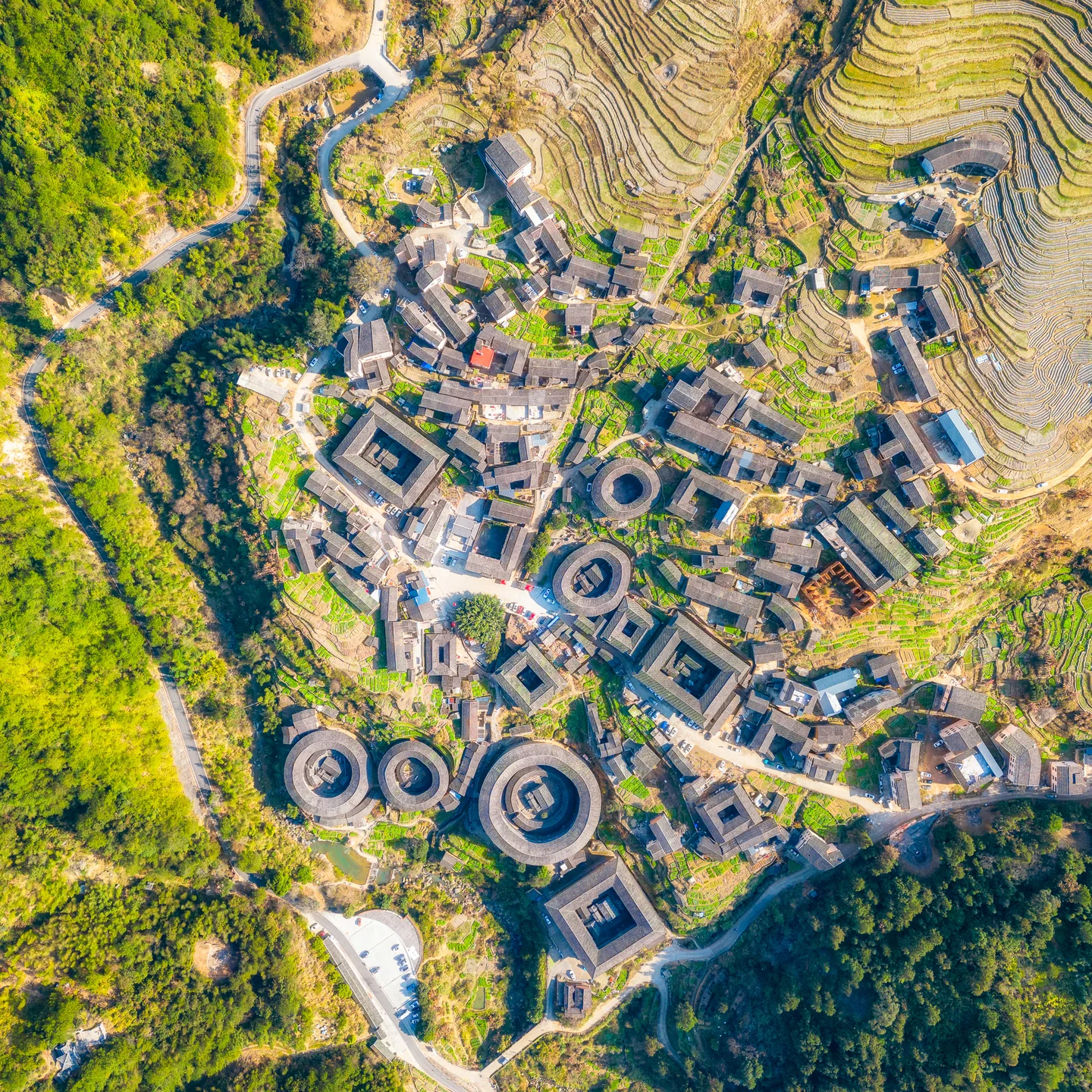 A cluster of circular earthen buildings and surrounding terraces, viewed from above.
