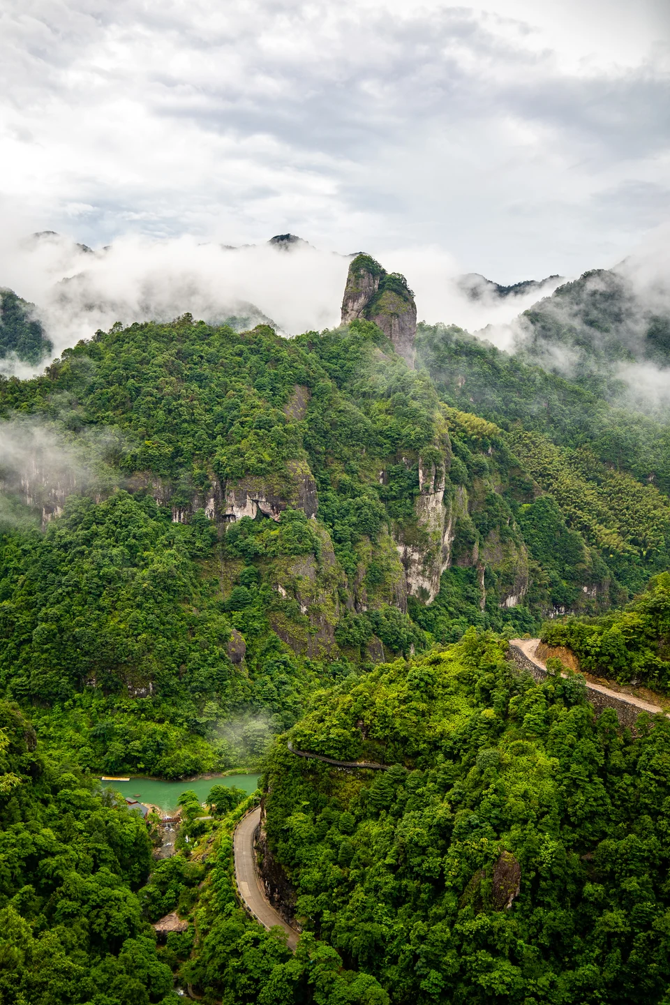 Clouds drift between green mountain peaks above a winding stone walkway.