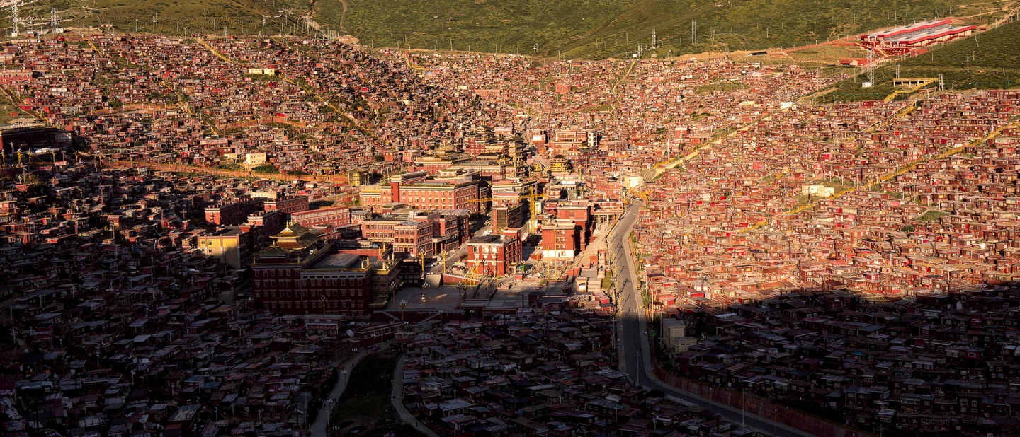 A broad mountain shadow crosses a dense hillside of red buildings.
